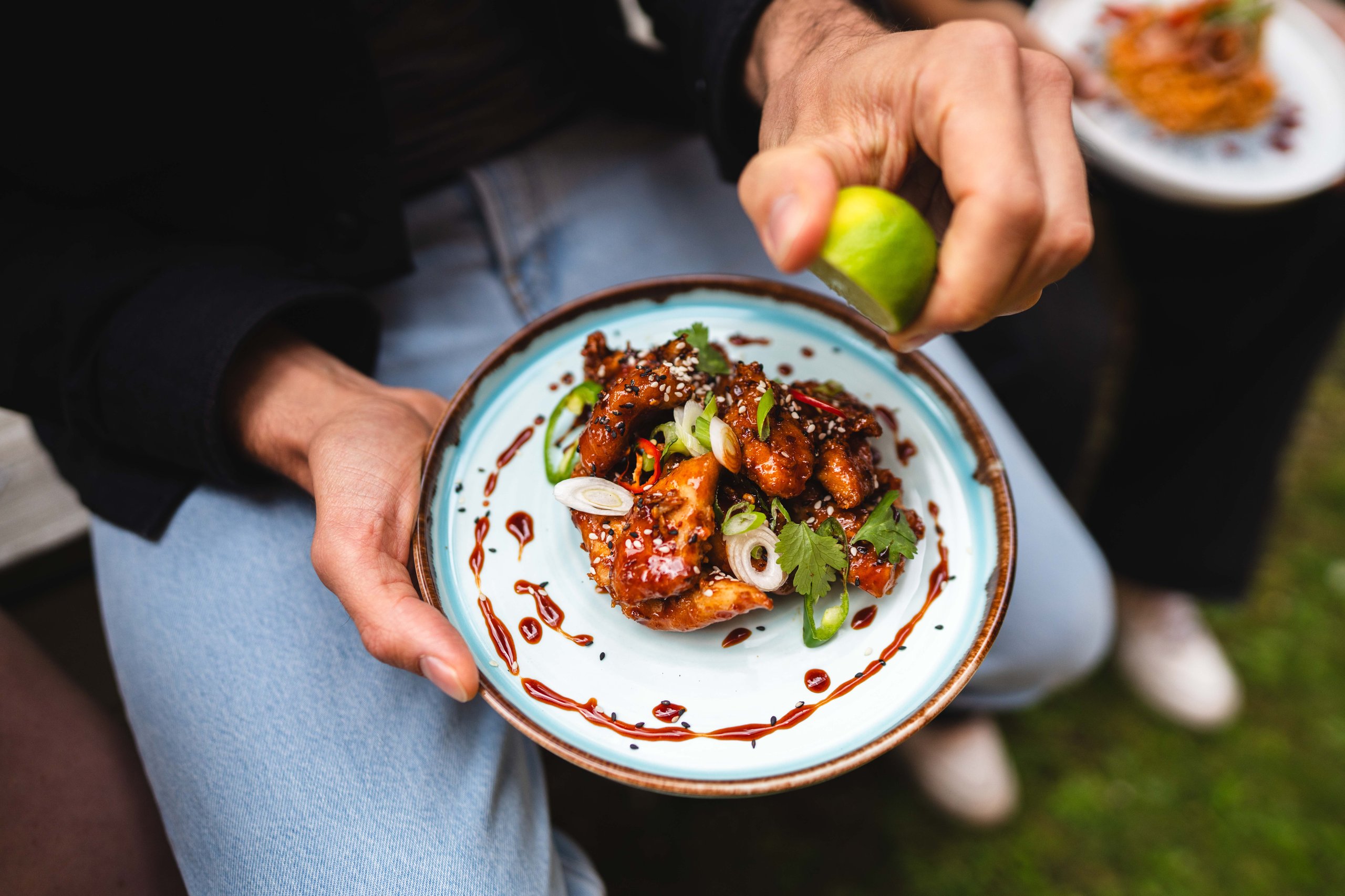 Person squeezing lime on chicken dish. Close-up.