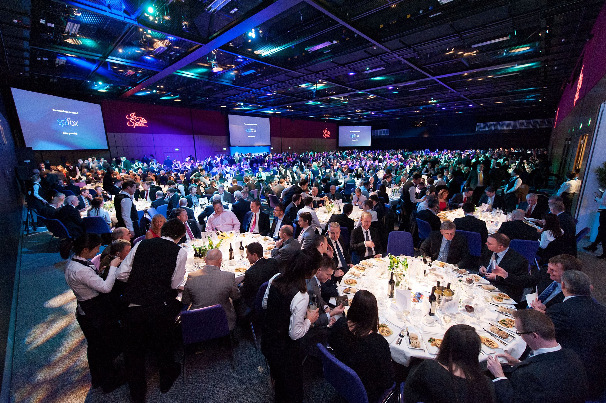 Large banquet hall with tables, waiters, and guests.
