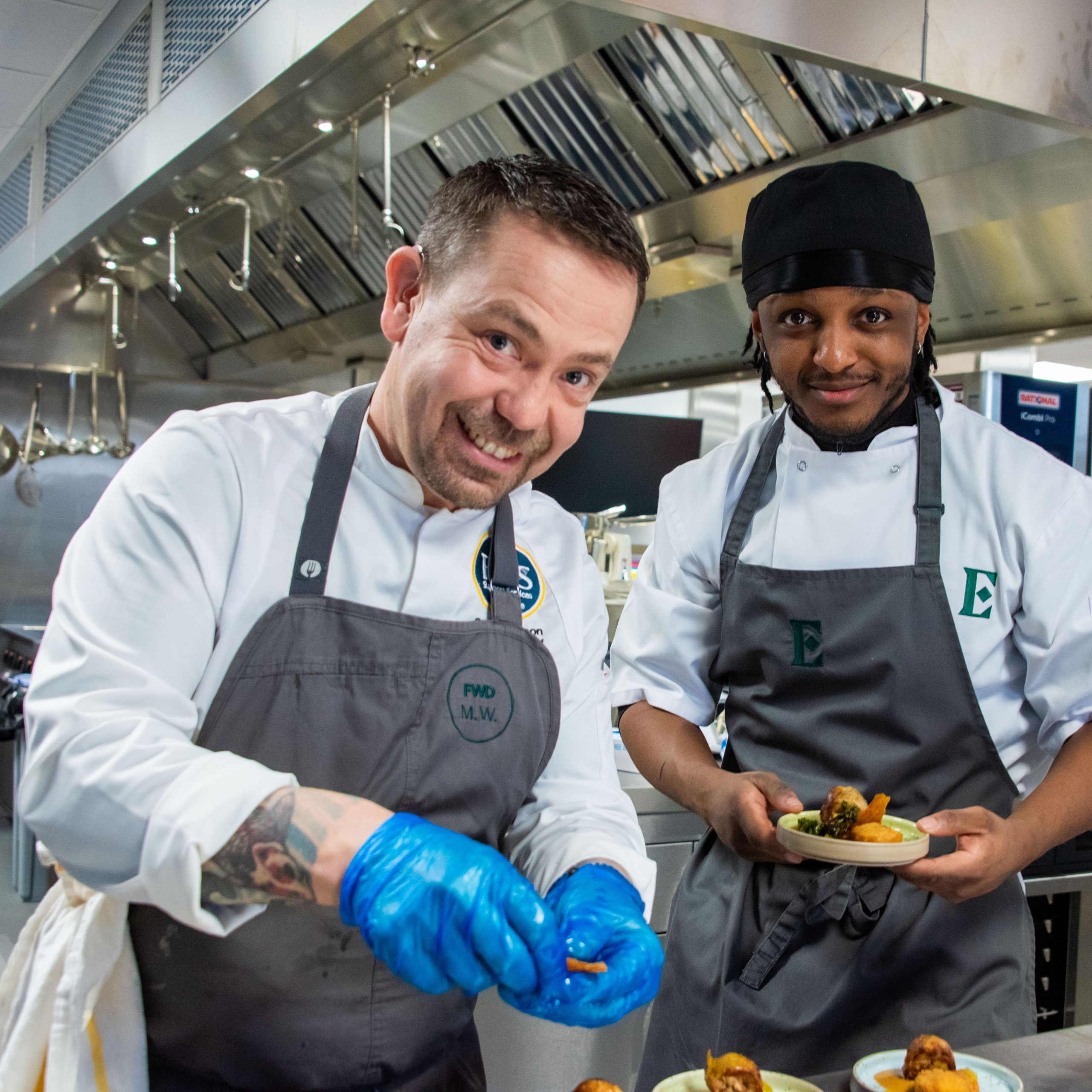 Two chefs in a commercial kitchen preparing food.