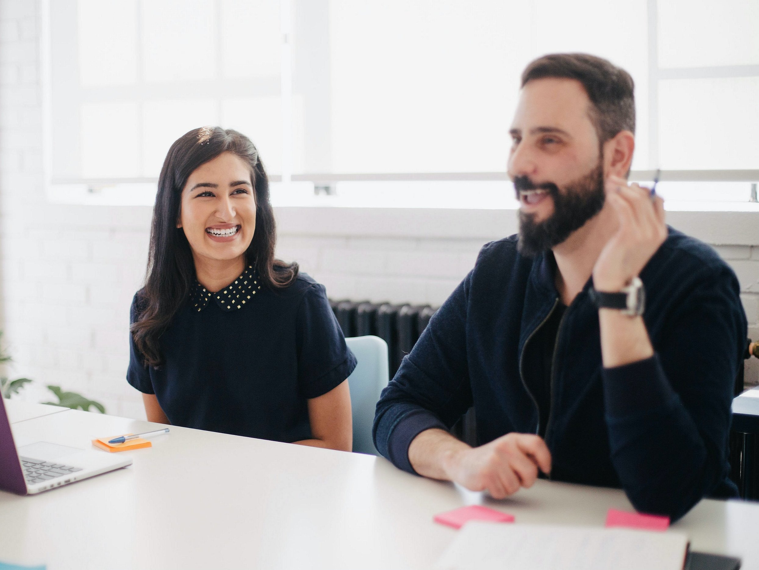 Two colleagues smiling at a meeting table.