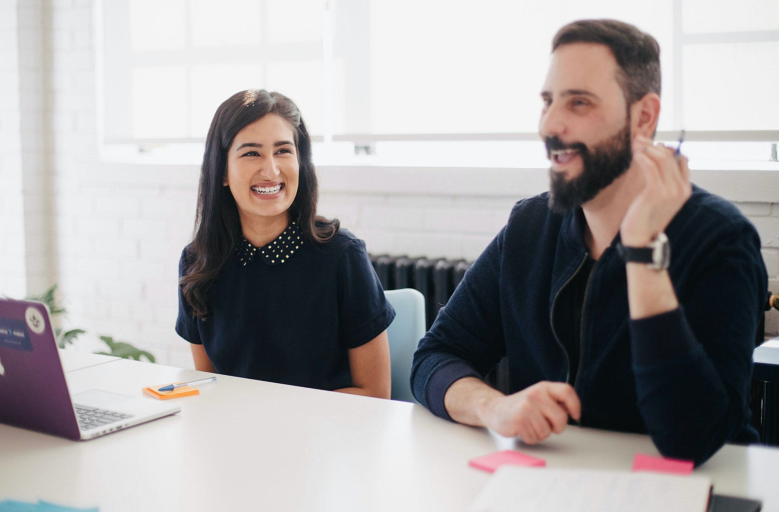 Two colleagues smiling at a meeting table.