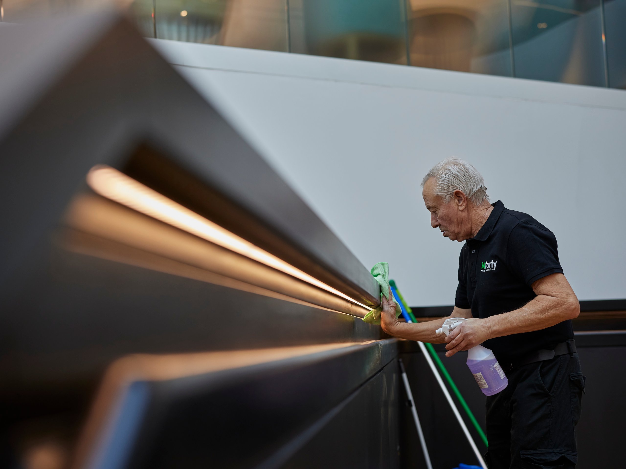 Person cleaning a handrail, spraying with cleaner.