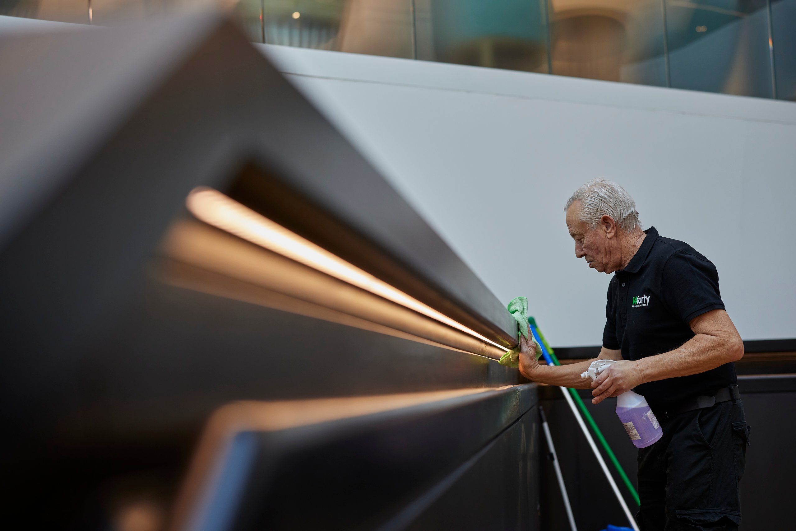 Person cleaning a handrail, spraying with cleaner.
