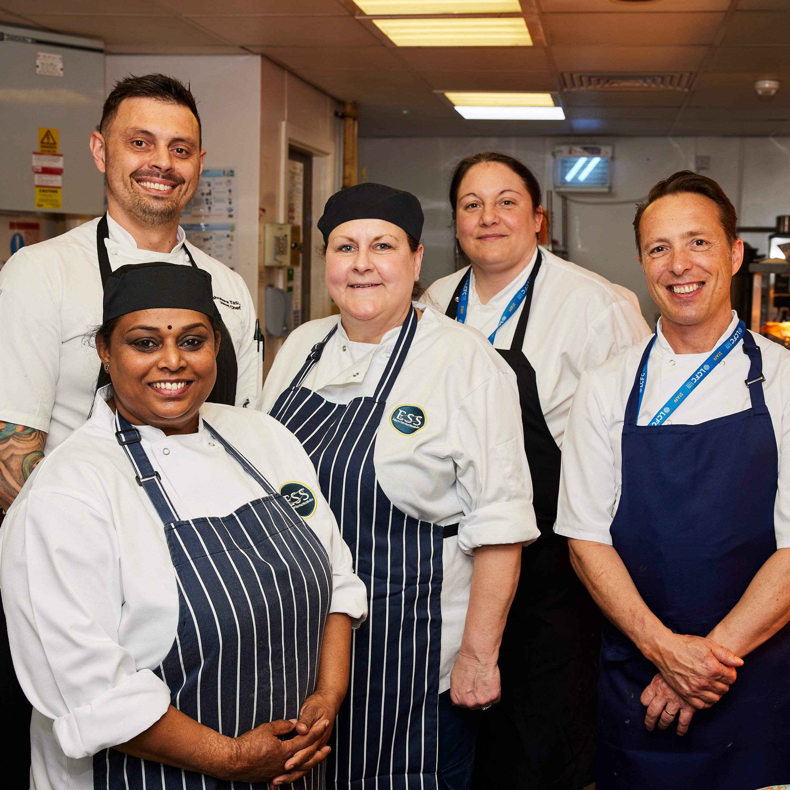 Group of chefs smiling in a kitchen setting.