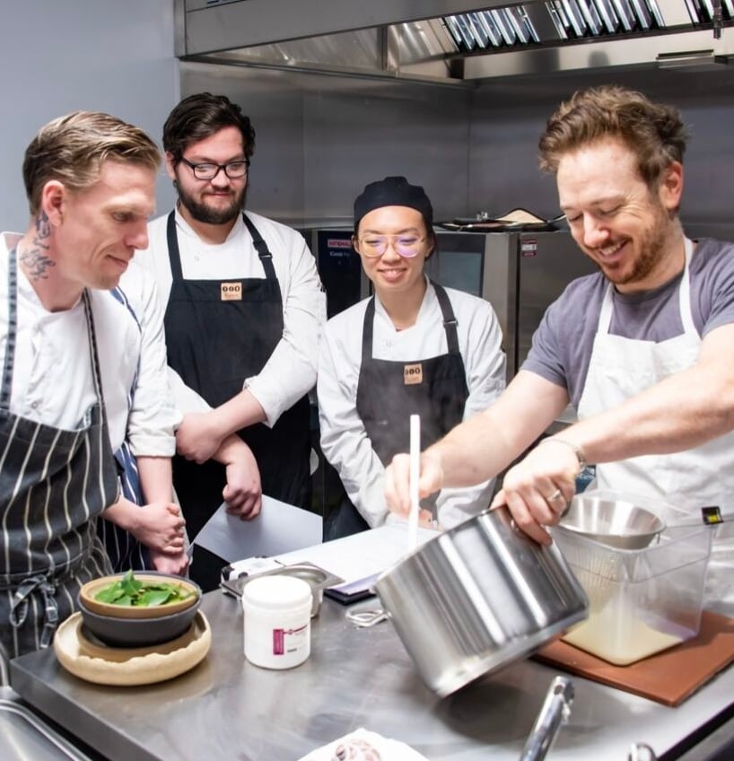 Chefs preparing food in a professional kitchen.