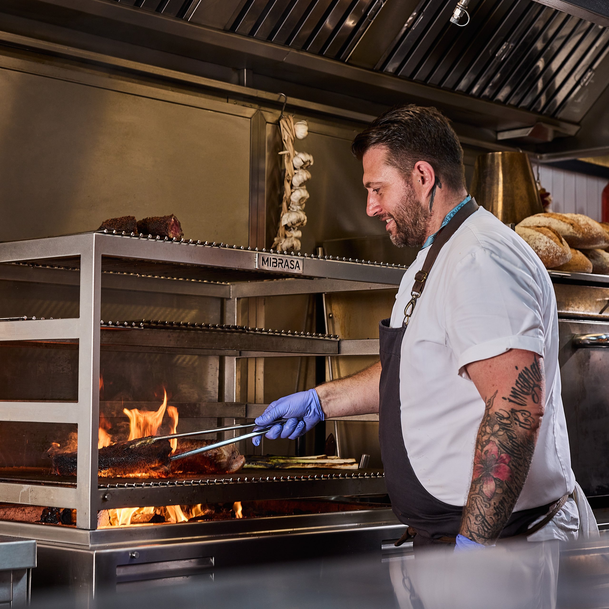 Chef cooking with flames in an industrial kitchen.