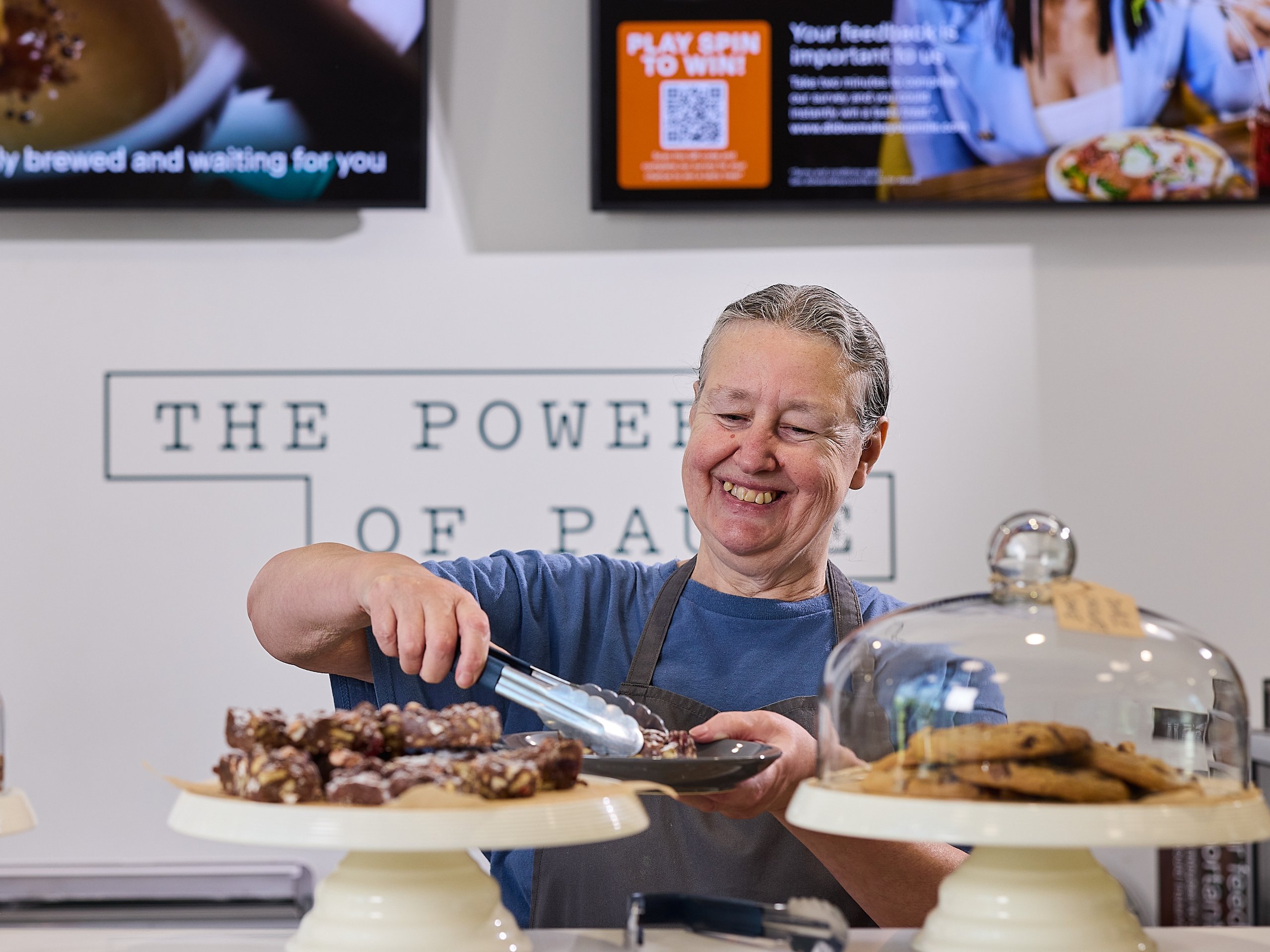 Woman using tongs to serve dessert with desserts in the foreground.