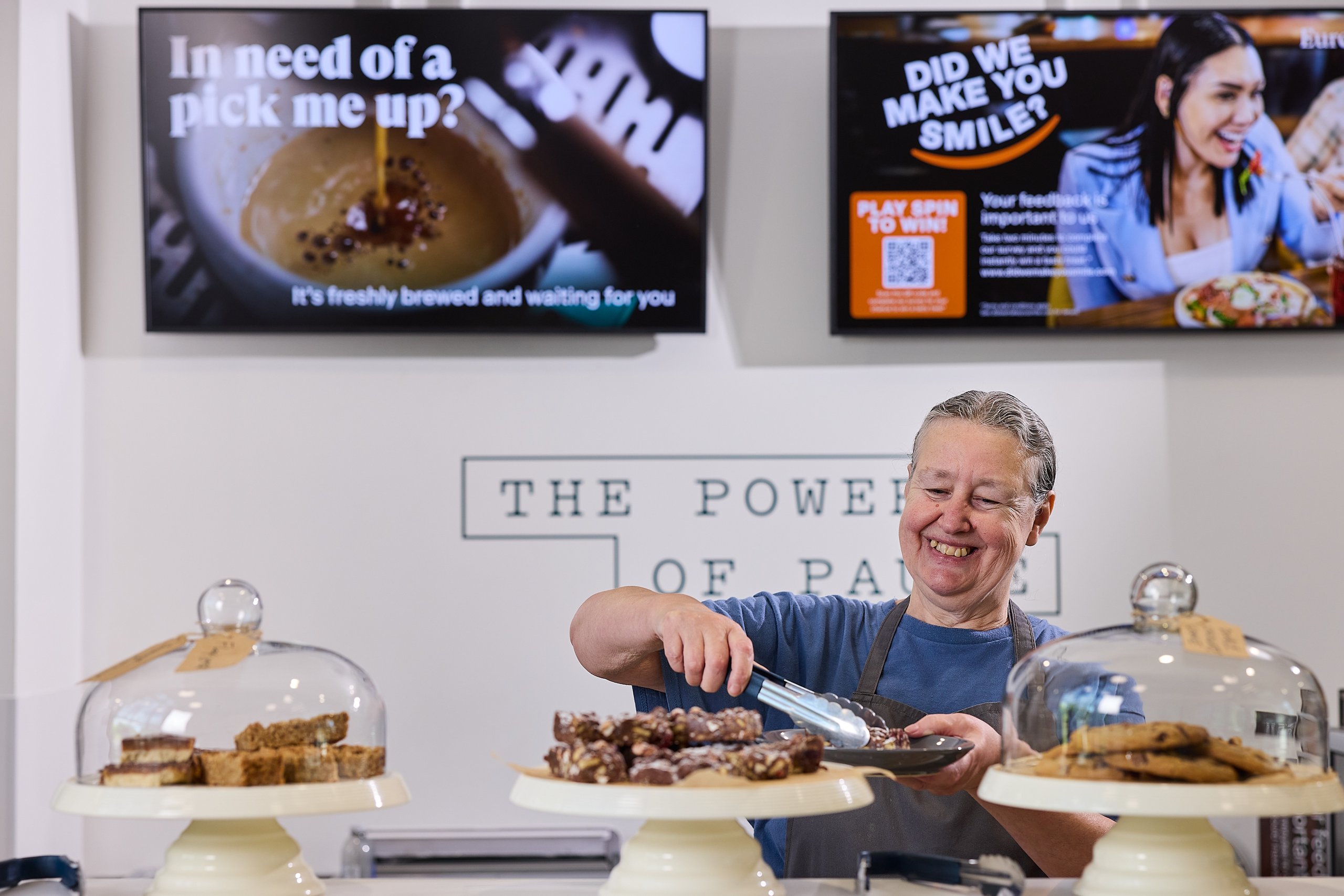 Woman using tongs to serve dessert with desserts in the foreground.