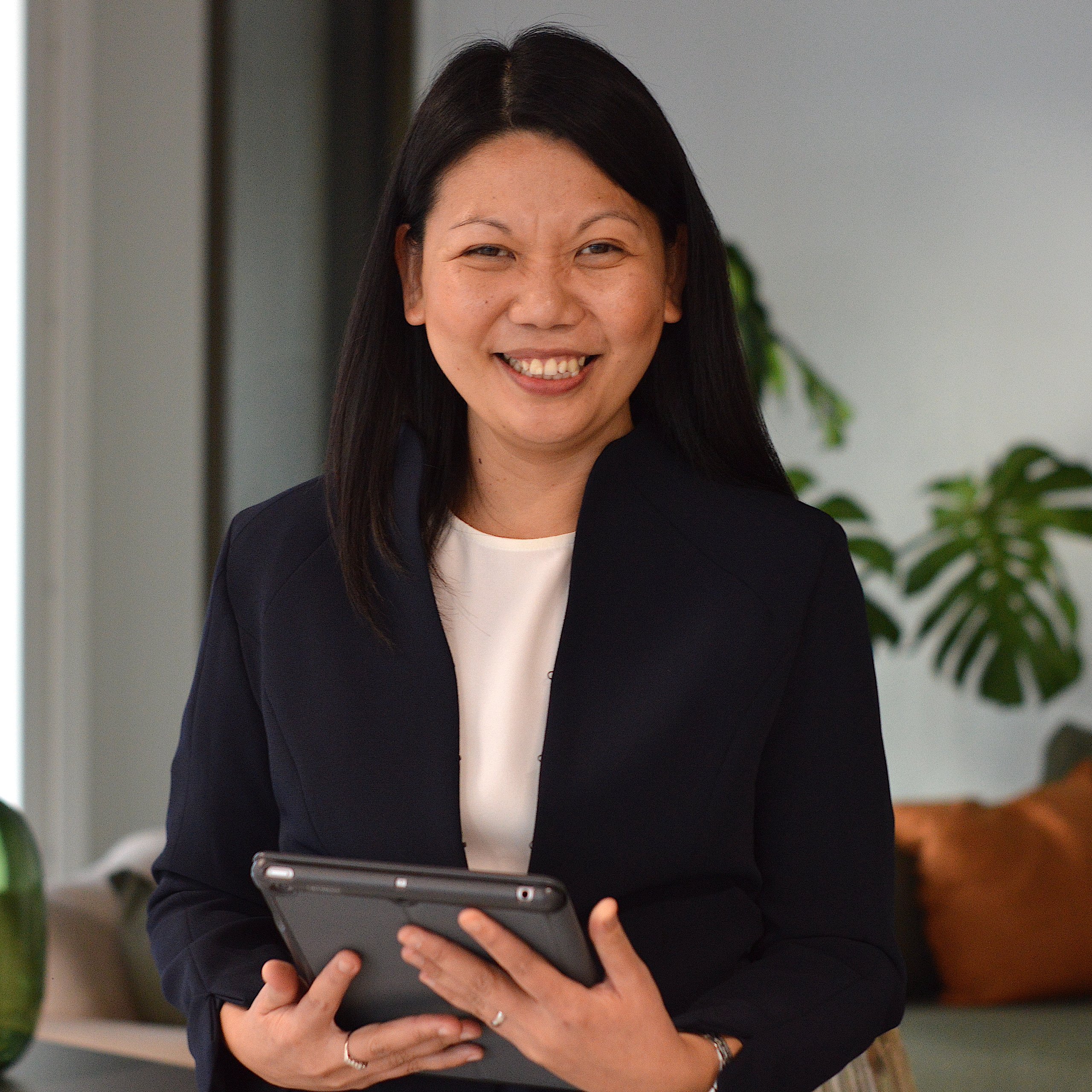 Woman holding a tablet, smiling.