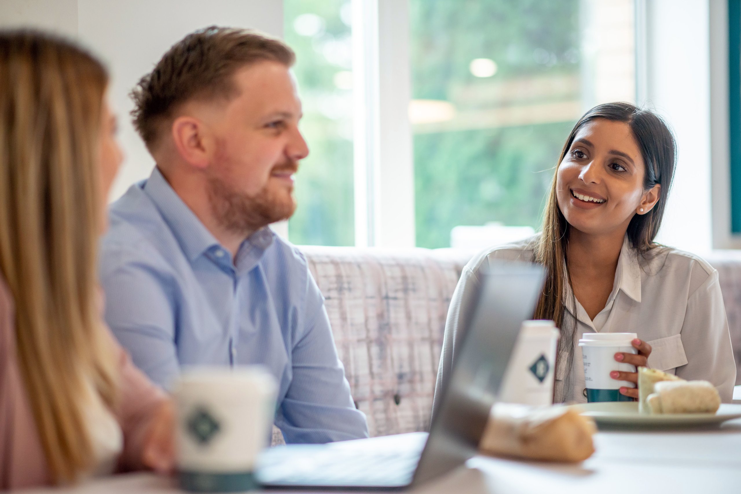 A group of people smiling and conversing in a cafe.