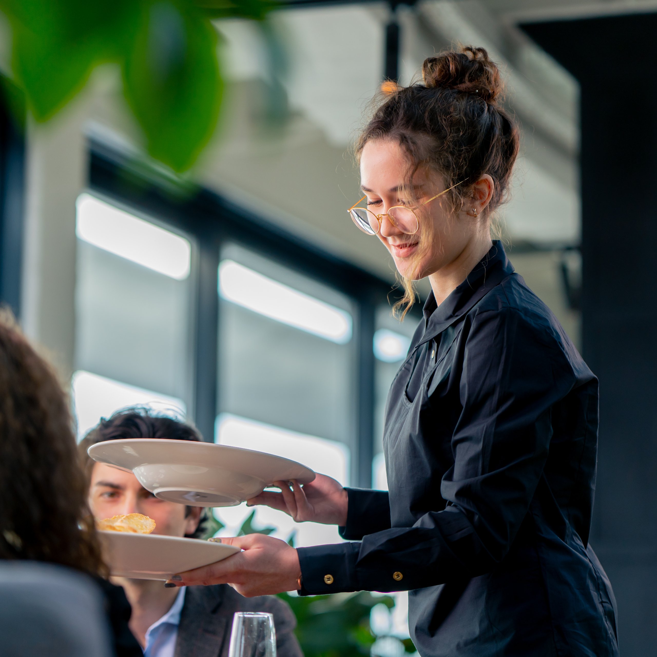 A waiter serving plates of food to customers in a restaurant.