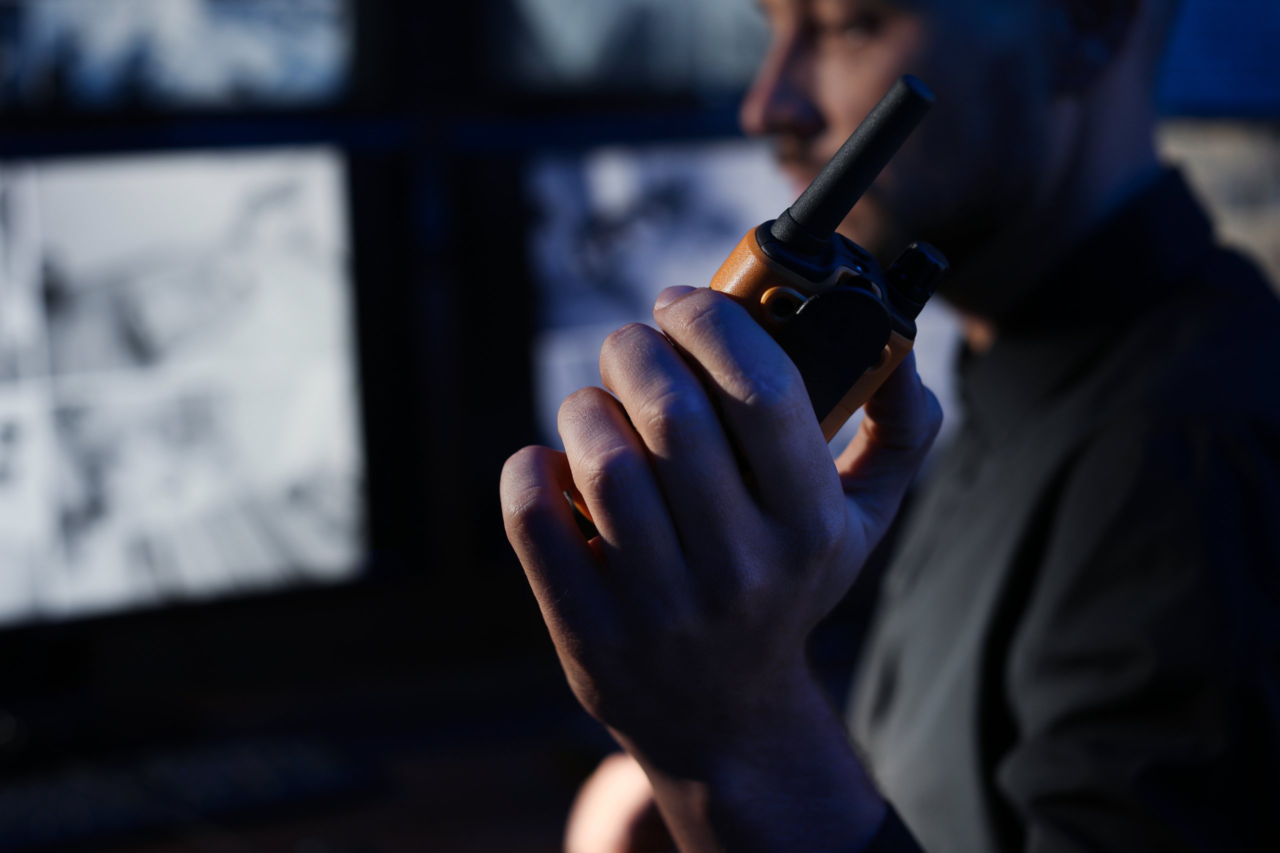 Security guard holding a radio, monitoring CCTV cameras.
