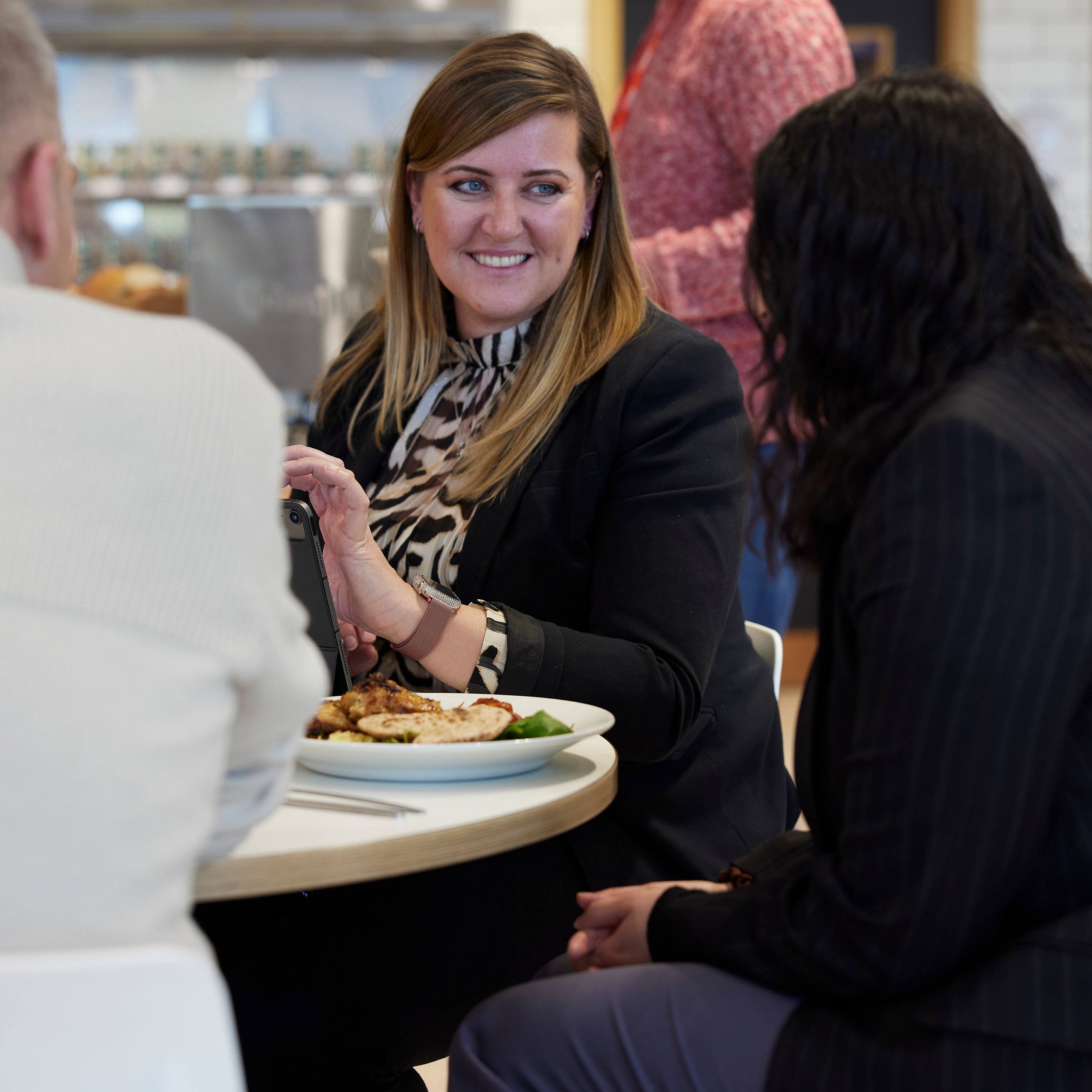 Three people at a table, discussing catering, one smiling.