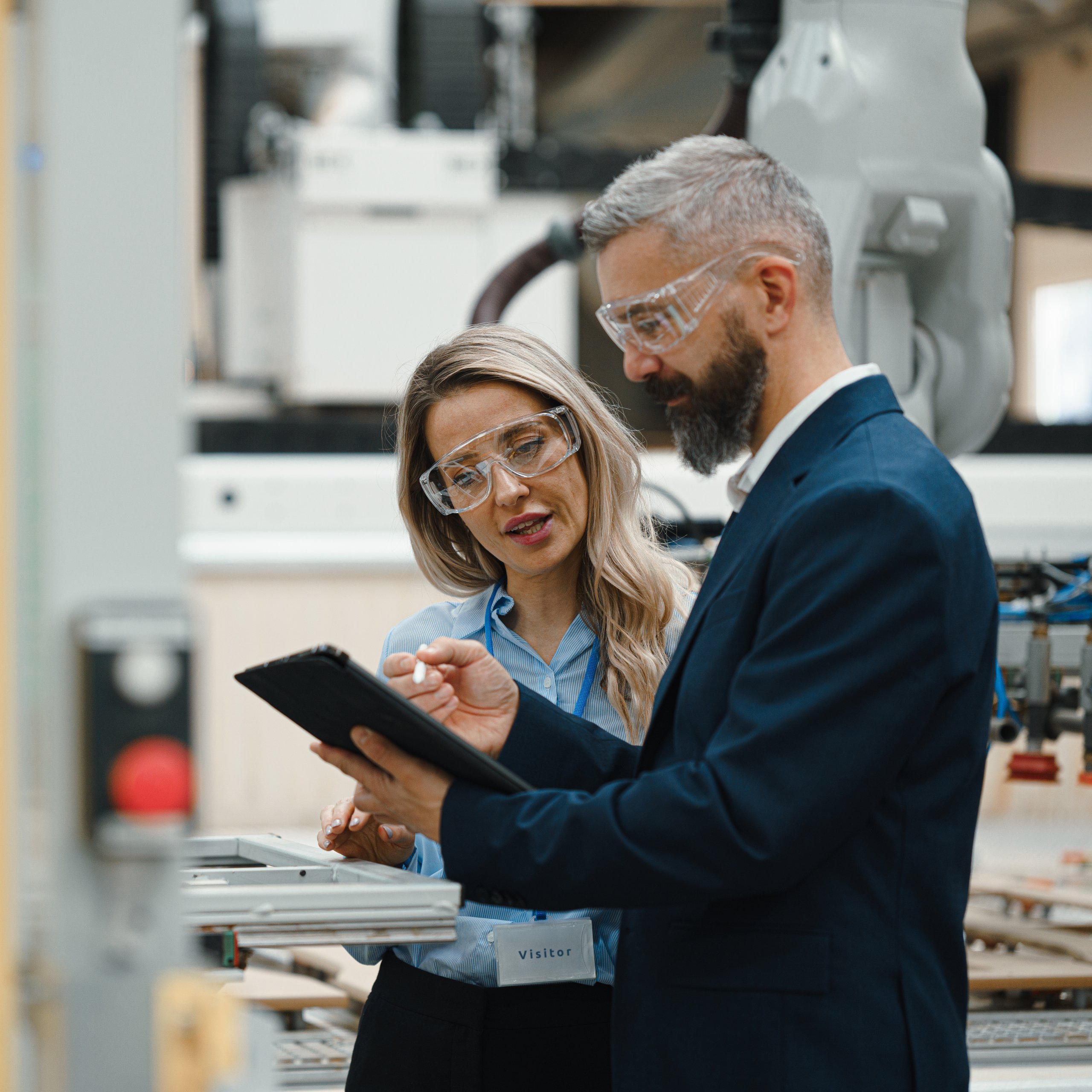 Two people in a manufacturing facility looking at a tablet.