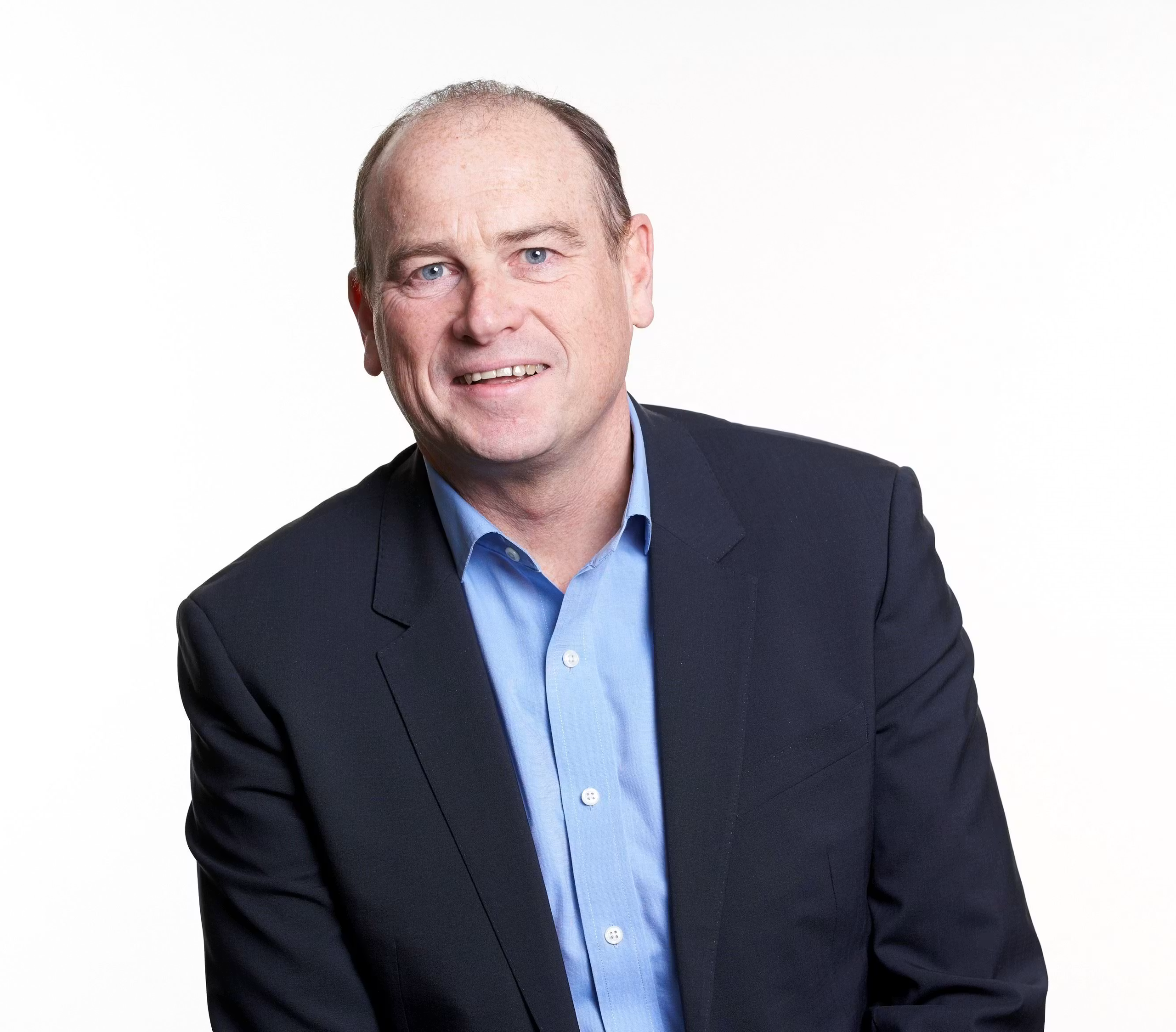Portrait of a middle-aged man in a blue button-down shirt and black blazer against a white background
